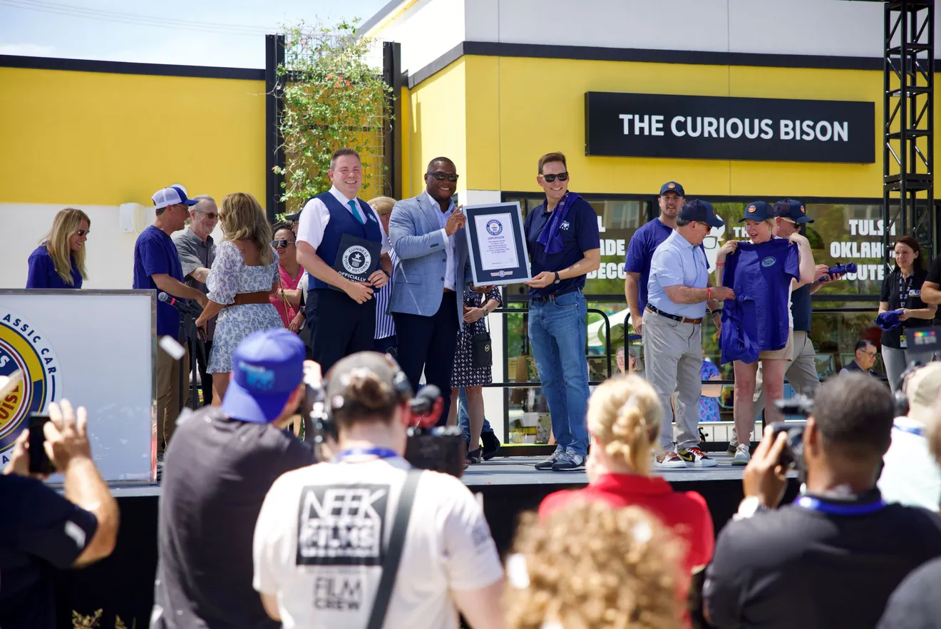 Officials on stage presenting the world record certificate for the parade, in front of 'The Curious Bison' building