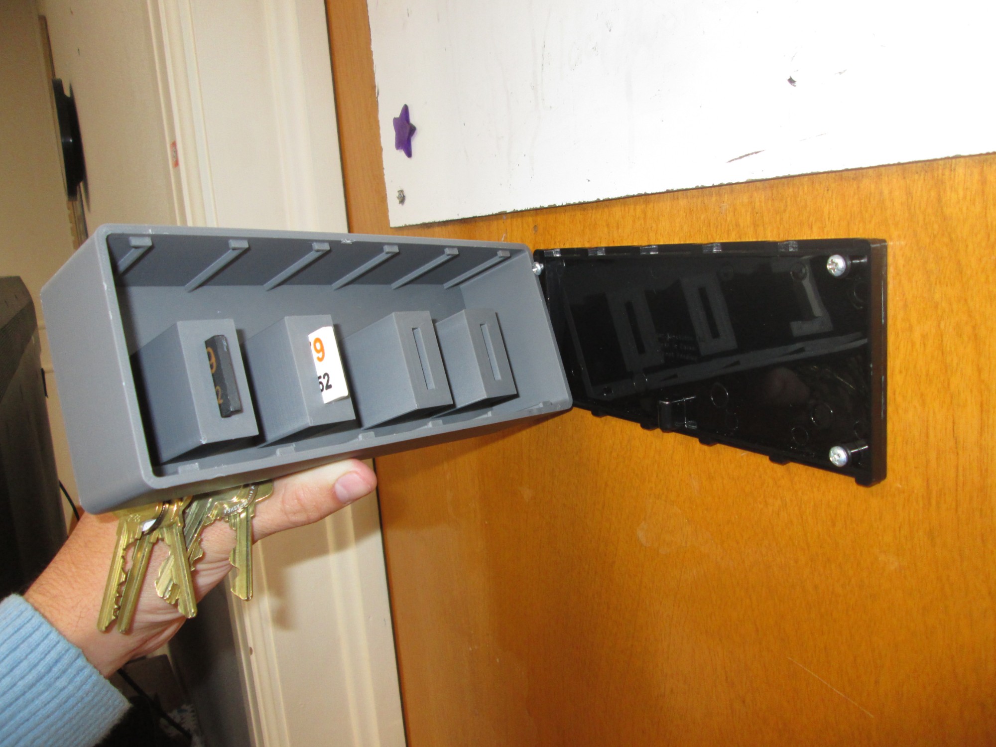 The key box detached from its wall mount, showing the internal key-slot compartments