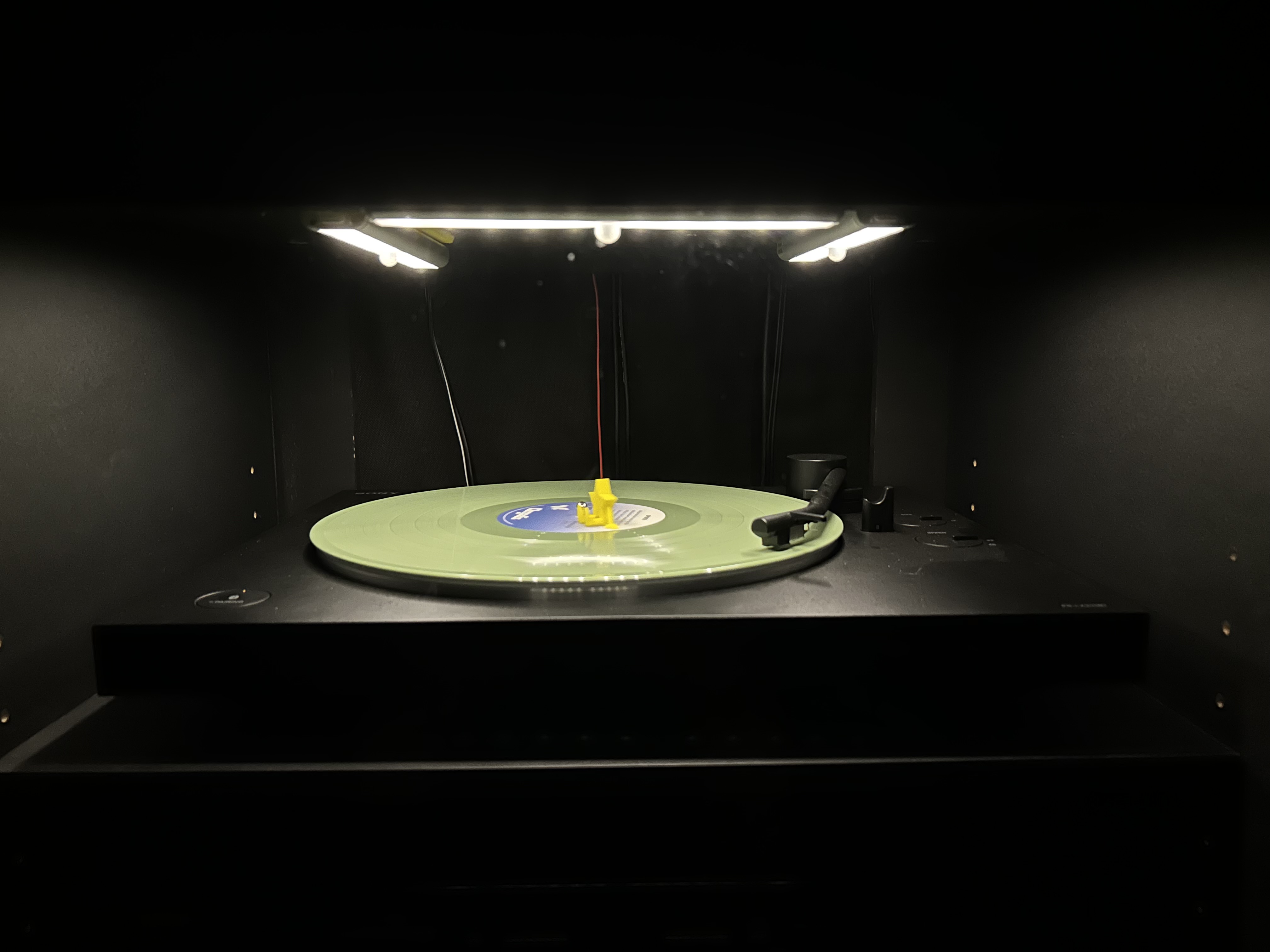 The light stick holders mounted above the turntable, lit up over a spinning record