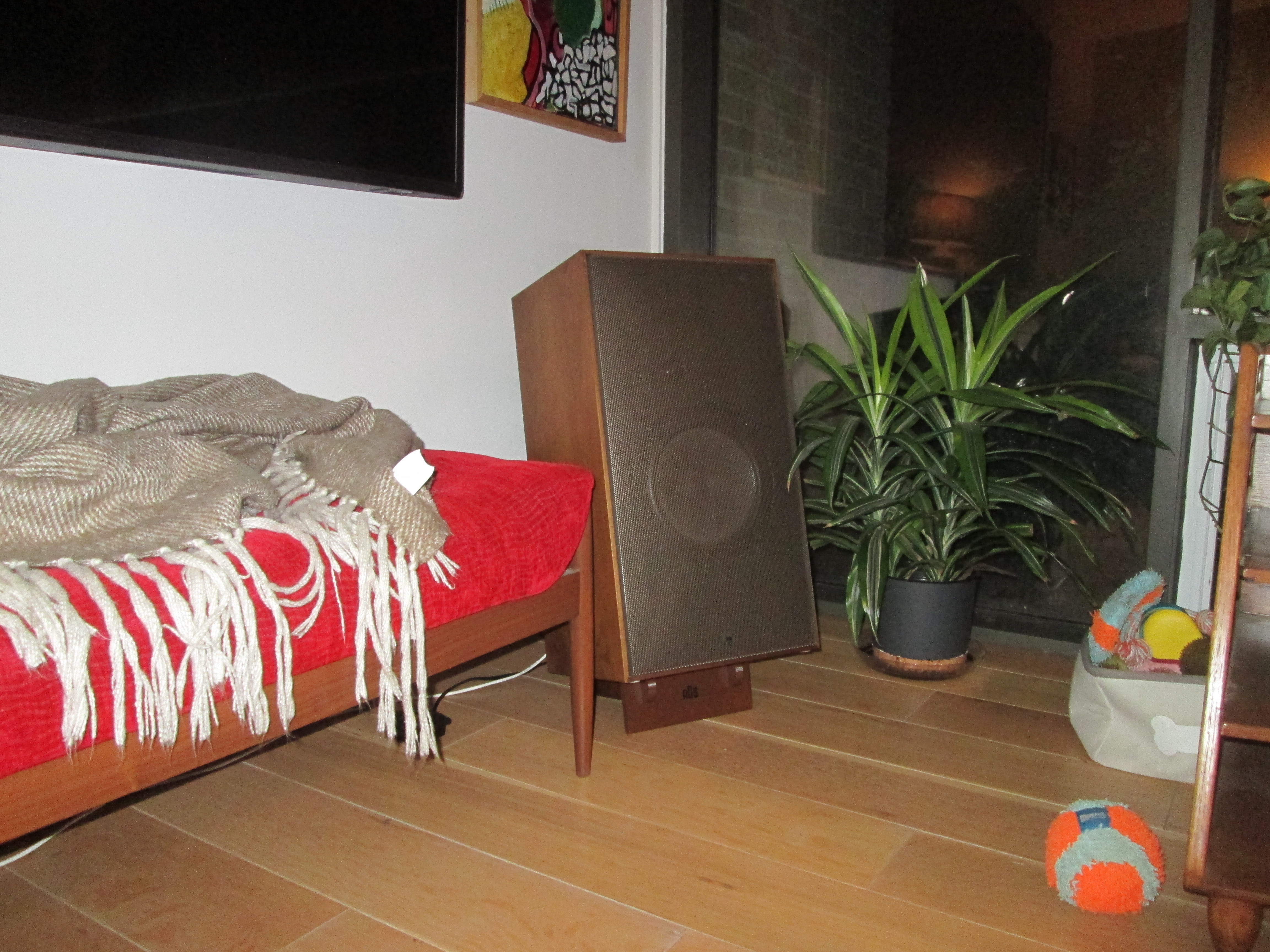 One vintage speaker resting on its two-piece printed riser next to the couch